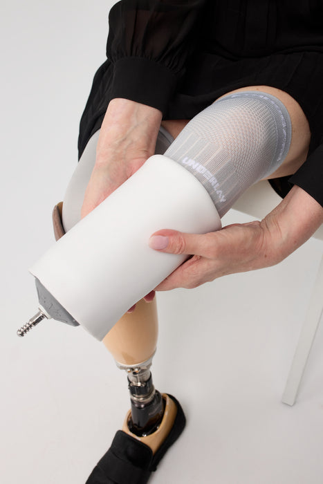 A close-up of a person putting on above their liner with the Ethnocare Underlay Transtibial Closed Prosthetic Sweat Management Device underneath. 