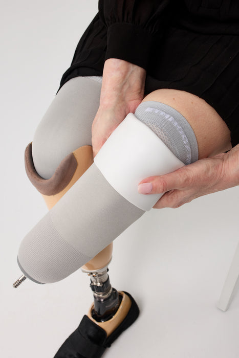 A close-up of a person finishing putting on liner with the Ethnocare Underlay Transtibial Closed Prosthetic Sweat Management Device underneath. 