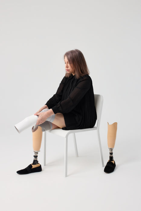 Person putting on above their liner with the Ethnocare Underlay Transtibial Closed Prosthetic Sweat Management Device underneath