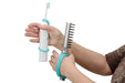 Hands holding a white electric toothbrush and a silver scrubber with bristles with an aqua EaZyHold Grip Aid on a white background