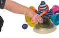 Child's hand playing with a colorful toy structure with a pink EaZyHold Grid Aid on a white background