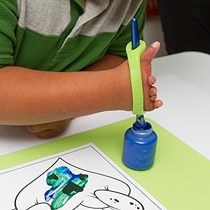 Child's hand using a paintbrush with a green EaZyHold Grip Aid to paint