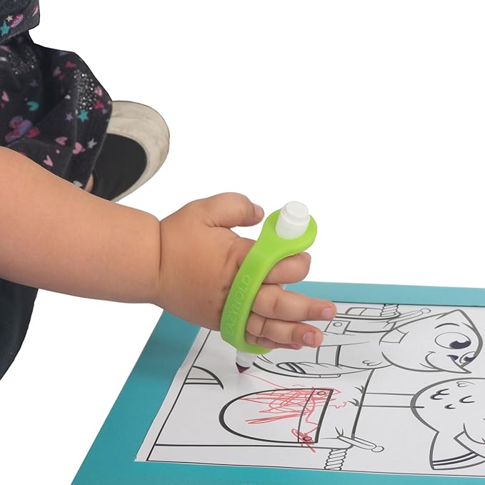 Child's hand holding a marker with a lime green EaZyHold Grip Aid over a coloring book with cartoon characters on a white background
