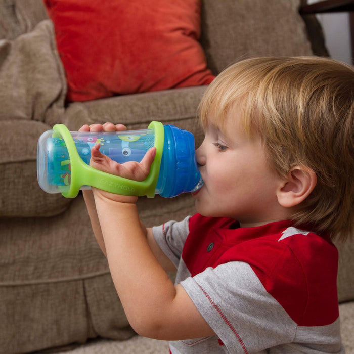 Child drinking from a blue sippy cup with an EaZyHold Grip Aid in a living room