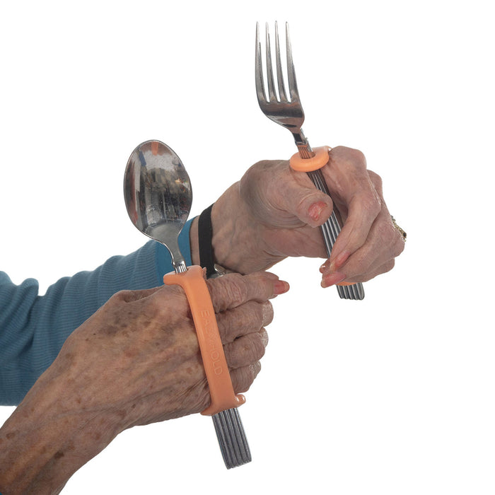 Hands holding a fork and spoon with an orange EaZyHold Grip Aids against a white background