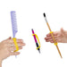 Hands holding a comb, pen, and paintbrush with a yellow EaZyHold Grid Aid on a white background