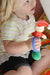 Child holding a colorful toy with a blue EaZyHold Grid Aid in the background