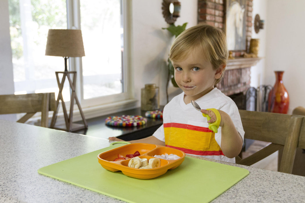 Child using a fork with an EaZyHold Grip Aid at a dining table
