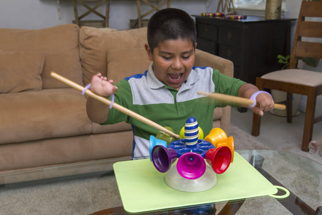 Child playing with a colorful toy held with a lavendar EaZyHold Grip Aid on a table in a living room.