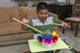 Child playing with a colorful toy held with a lavendar EaZyHold Grip Aid on a table in a living room.