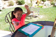 Young girl celebrating after writing on a portable whiteboard outdoors with an EaZyHold Grid Aid