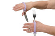 Person using a lavendar EaZyHold Grip Aid on a fork and knife against a white background