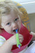 Child eating food with a spoon with an EaZyHold Grip Aid in a high chair