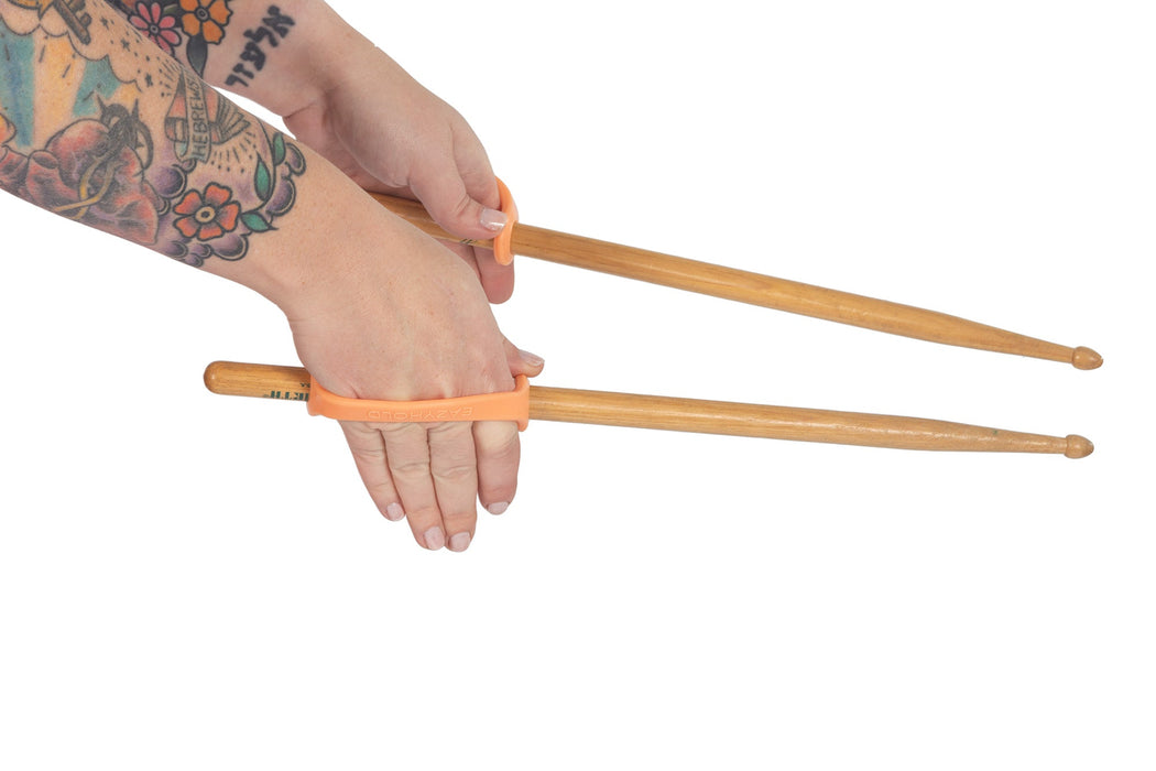 Drumsticks with an orange EaZyHold Grip Aids held by a hand on a white background