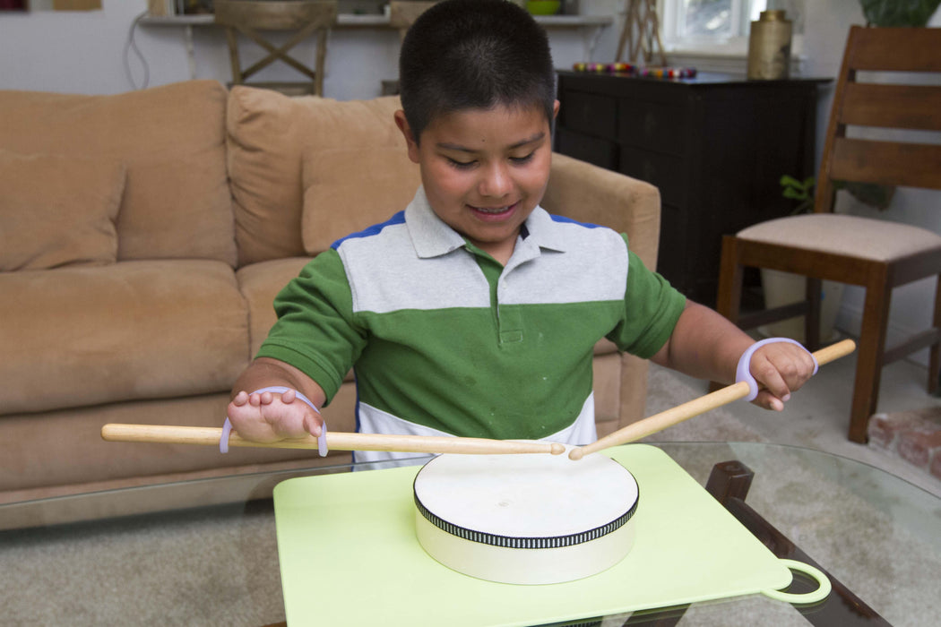 Child playing a small drum with a lavendar EaZyHold Grip Aid in a living room setting