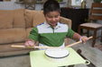 Child playing a small drum with a lavendar EaZyHold Grip Aid in a living room setting