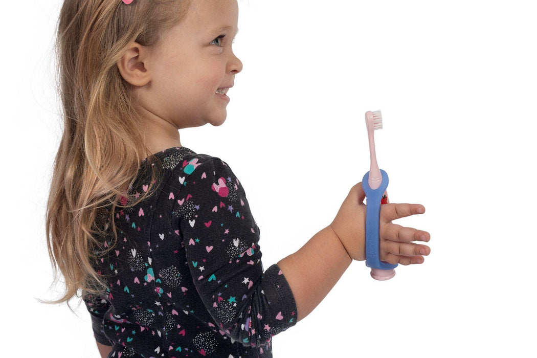 Child holding a and pink toothbrush with a blue EaZyHold Grid Aid on a white background