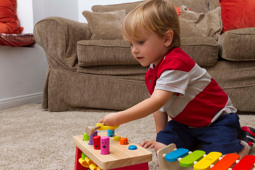 Child playing with a wooden toy held with an EaZyHold Grip Aid on a carpeted floor
