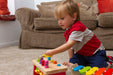 Child playing with a wooden toy held with an EaZyHold Grip Aid on a carpeted floor