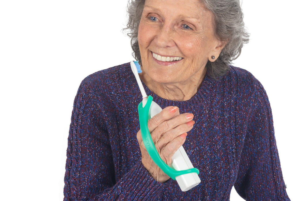 Woman holding a toothbrush with an EaZyHold Grid Aid on a white background