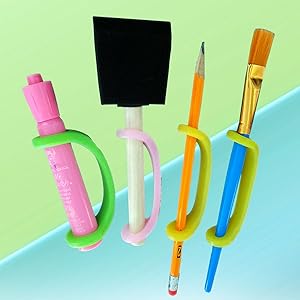 Set of colorful markers, paintbrush, and pencil with an EaZyHold Grip Aid on a light blue and green background