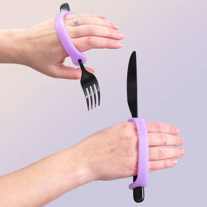 Person using a lavendar EaZyHold Grip Aid on a fork and knife against a light gray background