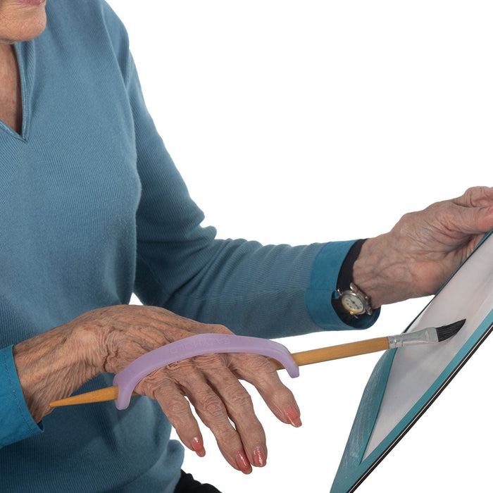 Person using a paint brush with a lavendarngreen EaZyHold Grip Aid on a white background
