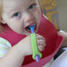 Child eating food from a spoon with a green EaZyHold Grip Aid