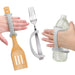 Hands holding a spatula, fork, and water bottle with a platinum EaZyHold Grid Aid on a white background