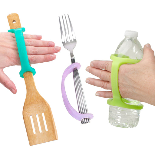 Hands holding a spatula, fork, and water bottle with an EaZyHold Grid Aid on a white background