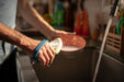 Person washing dishes in a kitchen with a navy EaZyHold Grip Aid