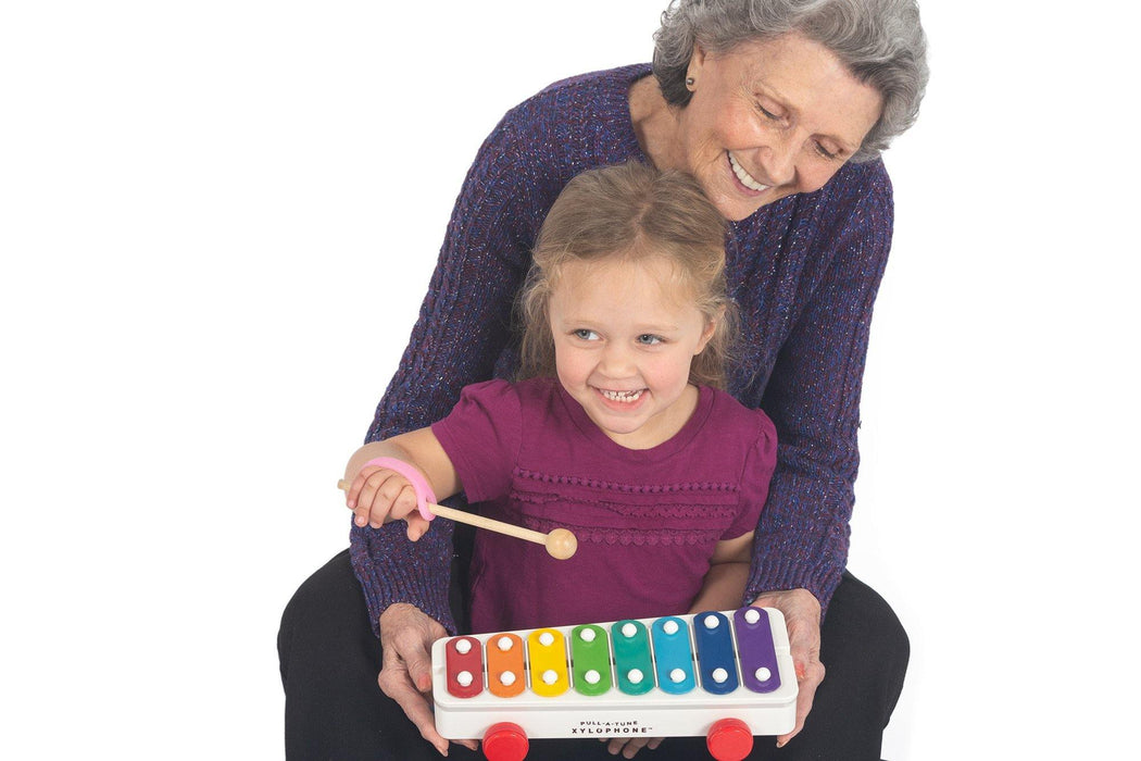 Grandmother and granddaughter playing with a colorful xylophone using an EaZyHold Grip Aid on a white background
