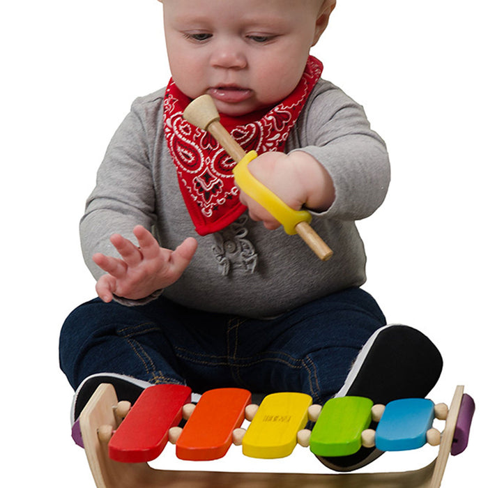 Baby playing with a colorful wooden held with an EaZyHold Grid Aid xylophone toy.