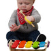 Baby playing with a colorful wooden held with an EaZyHold Grid Aid xylophone toy.