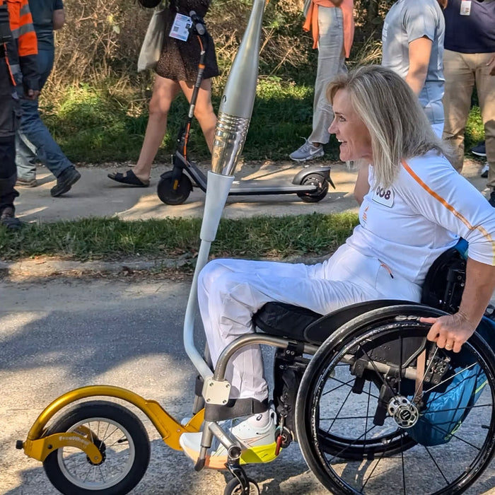 FreeWheel Wheelchair Attachment user bringing the torch to the 2024 Paralympic Games.