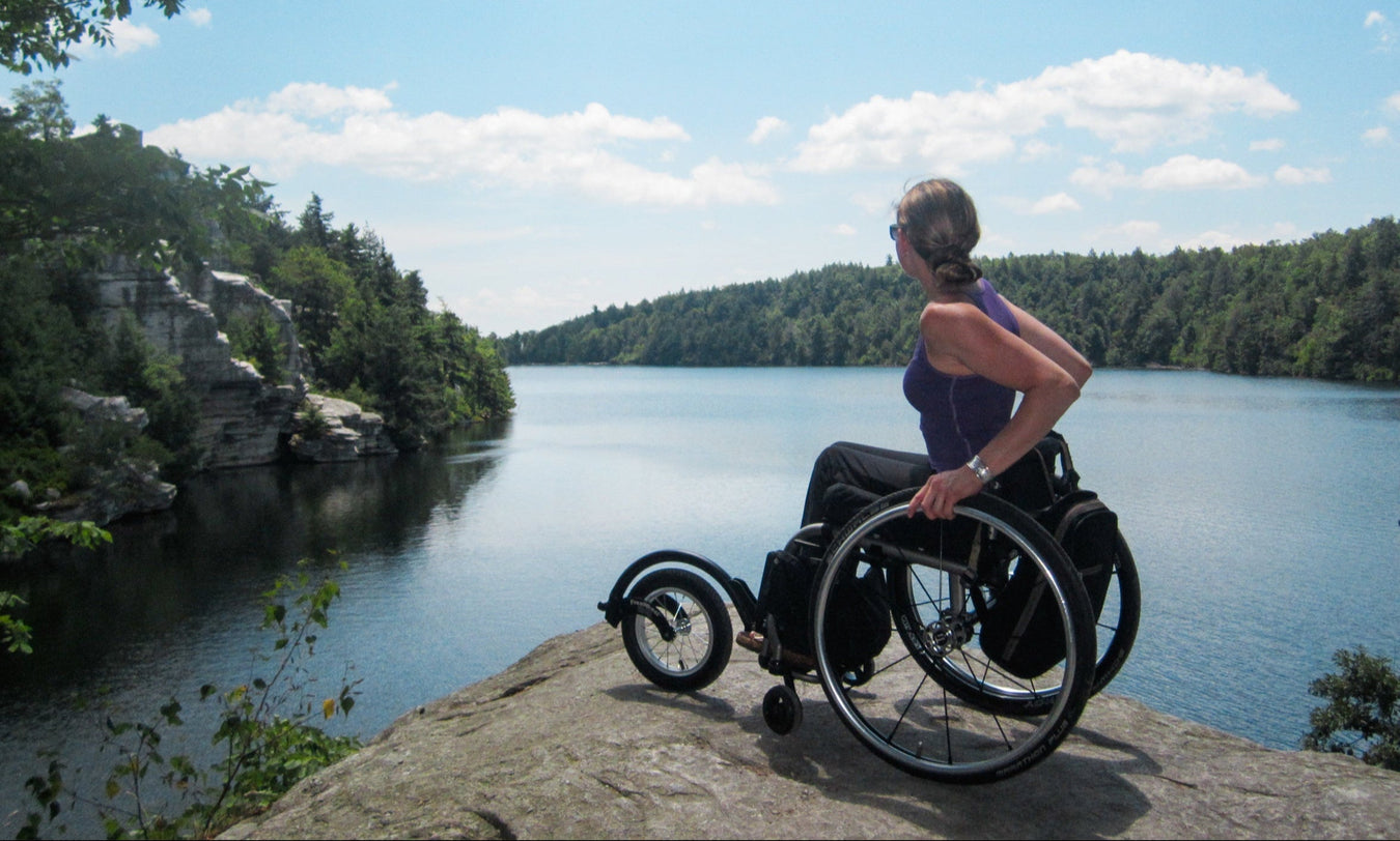 Person in a wheelchair using a FreeWheel overlooking a lake with a scenic view
