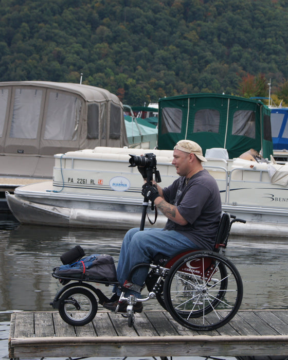 FreeWheel Wheelchair Attachment user using a camera on a tripod.