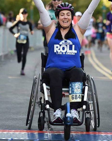 FreeWheel Wheelchair Attachment user crossing the finish line in a half marathon.