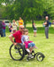 FreeWheel Wheelchair Attachment user pushing their kid on grass.