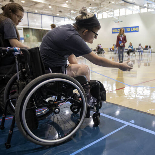 GLASA athletes using wheelchairs about to roll a boccia ball.
