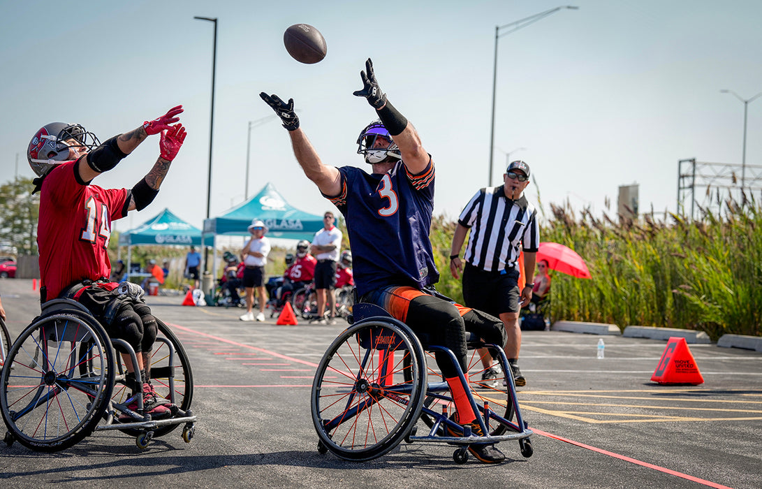 Chicago Bears Wheelchair Football player catching a pass against a Tampa Bay Bucs player.