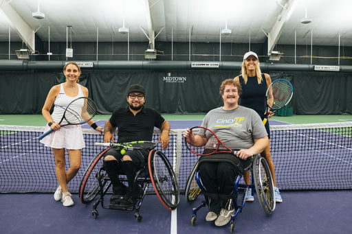 Portrait of four people, two from Great Lakes Adaptive Sports and two from Cincinnati Tennis Foundation on an indoor tennis court, two of whom are using tennis wheelchairs.