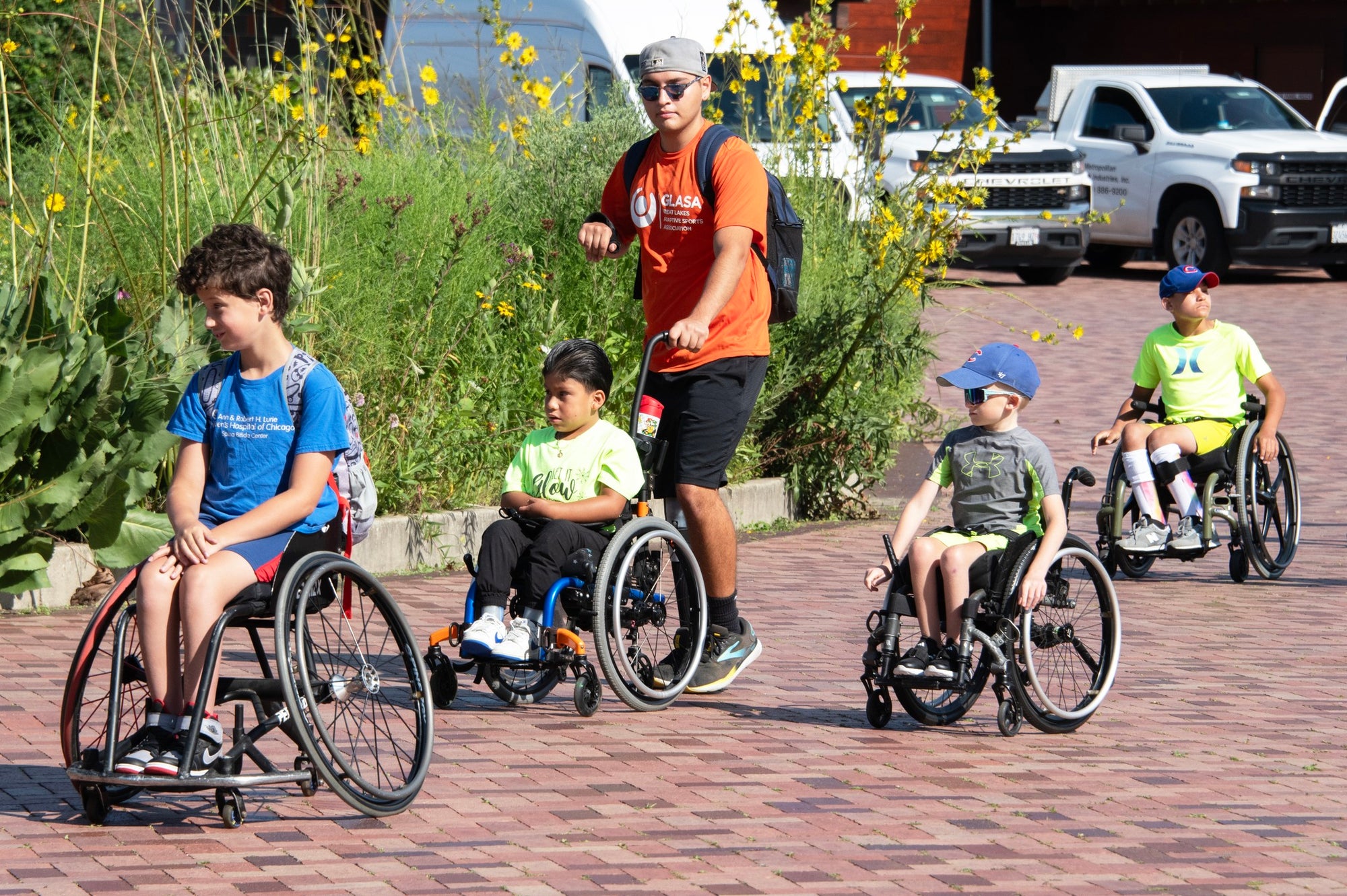 Group of youth GLASA athletes using wheelchairs getting ready to kayak with a GLASA volunteer.