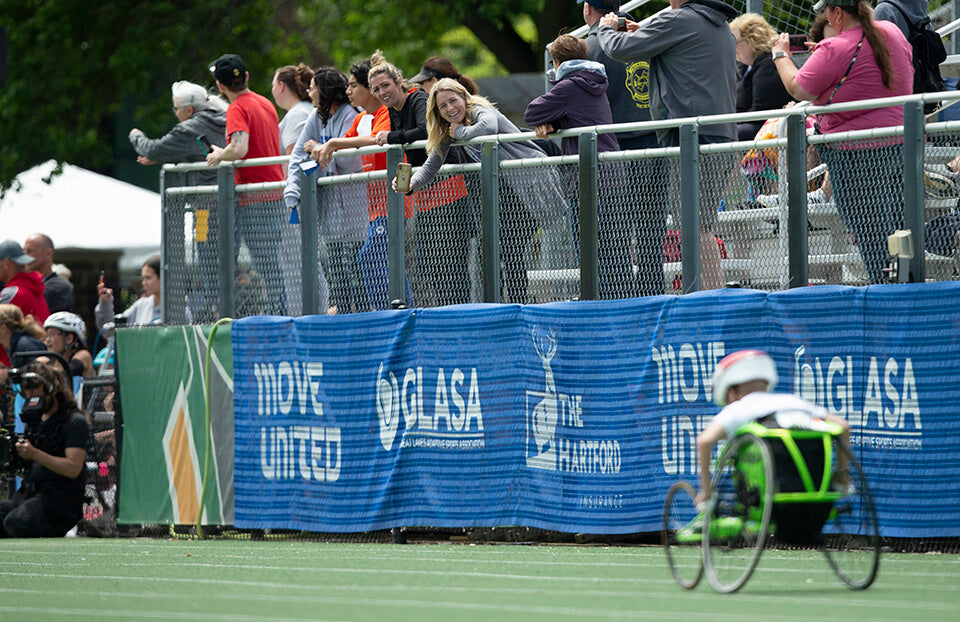 Fans cheering on an athlete in a wheelchair track race at the Great Lakes Games.