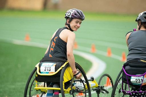 GLASA wheelchair racing athlete smiling on the racetrack while looking back at the camera.