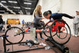 GLASA athletes in a row using a roller with a racing wheelchair with a coach helping them with technique.