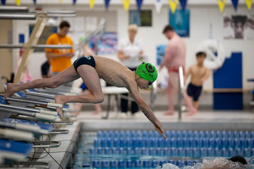 Swimmers diving to start a race at the Great Lakes Games.
