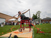GLASA athlete about to throw a javelin while strapped to an elevated chair in a track & field meet.
