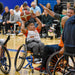 GLASA Wheelchair basketball game on an indoor court with a kid getting ready to shoot the basketball and an adult attempts to block them 