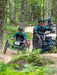 Three individuals from Green Mountain Adaptive Sports on adaptive mountain bikes navigating a forest trail